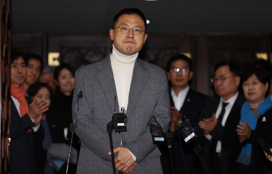 지난 12월7일 윤석열 대통령 탄핵소추안 표결 투표를 마친 김상욱 국민의힘 의원이 국회 본회의장 앞에서 기자회견을 하고 있다.  뒤는 김 의원을 응원하는 더불어민주당 의원들. 김 의원은 탄핵 표결엔 참여했지만 '반대'에 투표했다고 밝혔다.<연합뉴스 사진>